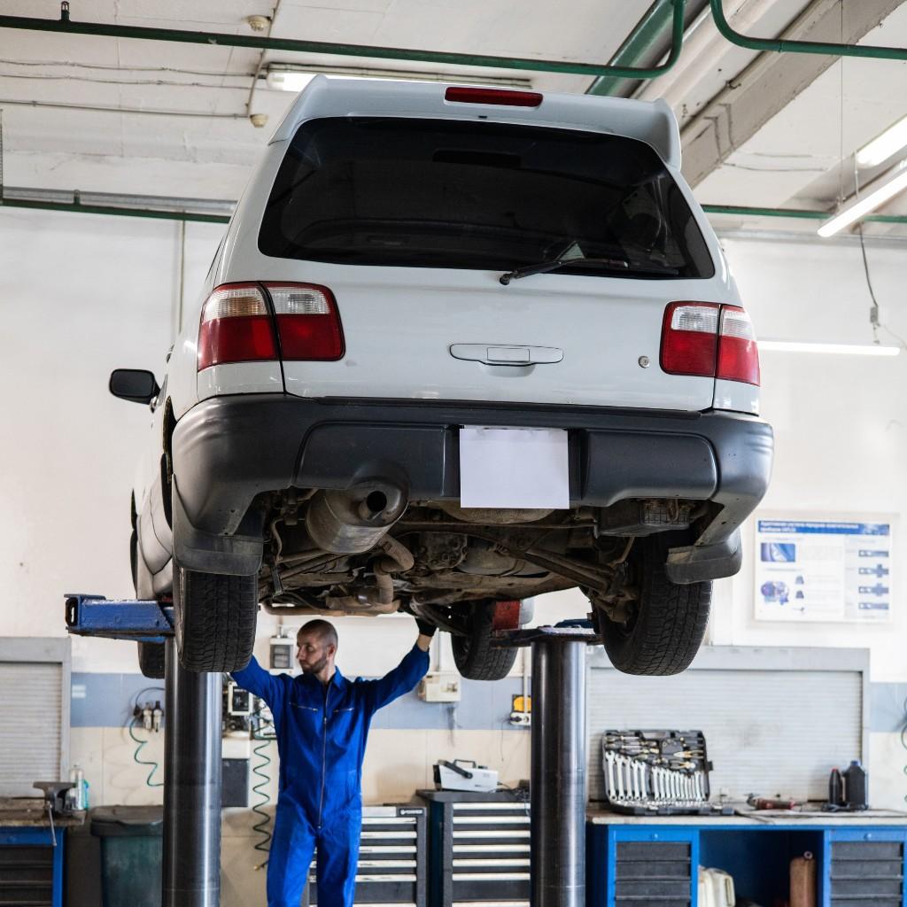 Car on a lift while a mechanic works underneath
